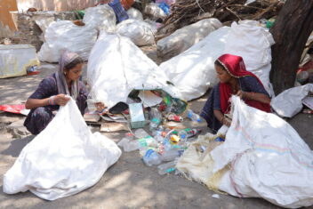 Two women sorting through plastic bottles