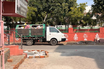 Waste collection vehicle going past a typical pink Jaipur wall