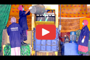 Play icon overlaying a picture of three women in blue safety coats loading plastic into a baling machine